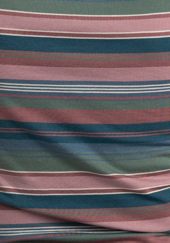 A close-up of the Layla V Neck Top - Adirondack 2.0 Stripe by Woolx showcases its multicolored striped fabric, featuring horizontal bands in shades of green, pink, blue, and brown. Made from Merino wool, this performance top has a subtle wrinkle that adds texture to the pattern.