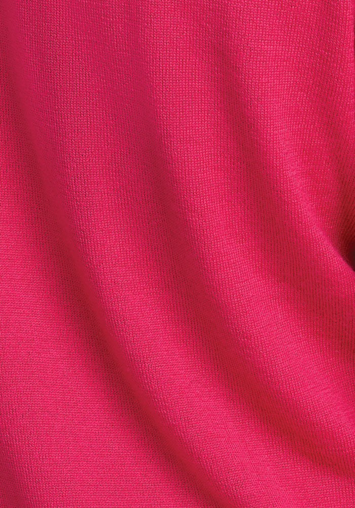 Close-up of the textured fabric of the Francesca Sweater in Berry Burst from Woolx, featuring a bright pink color with a smooth surface and subtle folds. The material looks soft, highlighting its vibrant hue.