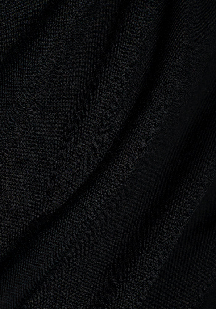 Close-up image of the Woolx Endi Full Button Down Shirt - Black fabric, showcasing its smooth texture and soft, flowing folds, highlighting the delicate interplay of light and shadow.