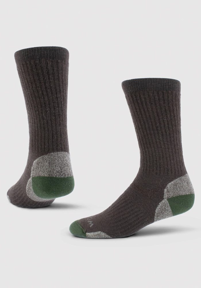 A pair of Woolx Core Crew Sock Full Cushion in French Roast, expertly crafted from moisture-wicking Merino wool, showcases contrasting green toes and gray heel accents, displayed standing upright on a light background.