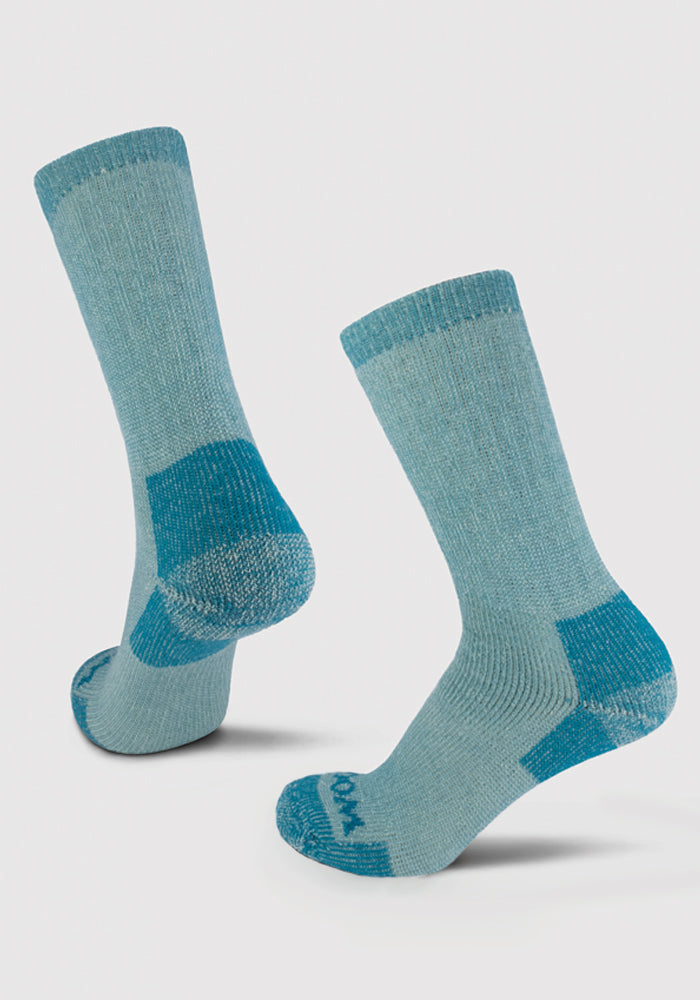 The Woolx Extreme Full Cushion Crew Socks in Real Teal, made from merino wool for exceptional warmth, showcase darker teal accents on the toes, heels, and cuffs. These ribbed socks are elegantly presented against a light gray background.