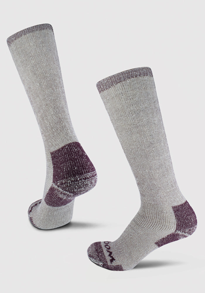 The Woolx Extreme Full Cushion Over The Calf Socks in Windsor Wine feature a heavyweight merino wool construction with purple accents at the toes, heels, and cuffs. They stand upright against a plain white background, with one sock slightly higher than the other to highlight their texture and design.