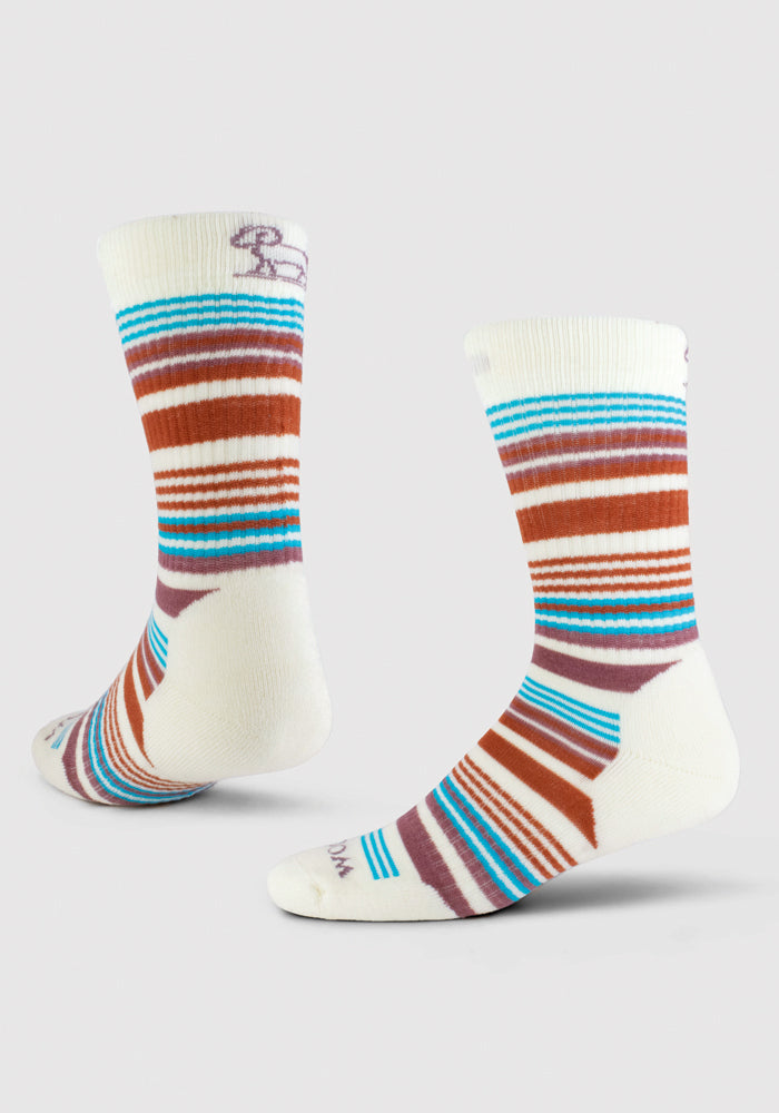 Discover the Everyday Crew Sock Light Cushion by Woolx, showcasing a natural stripe design in white with red, blue, and brown horizontal bands. Made from Merino wool for durability and moisture-wicking comfort, these socks feature a playful pattern and a subtle design detail near the top. They are styled to highlight both side and back views.