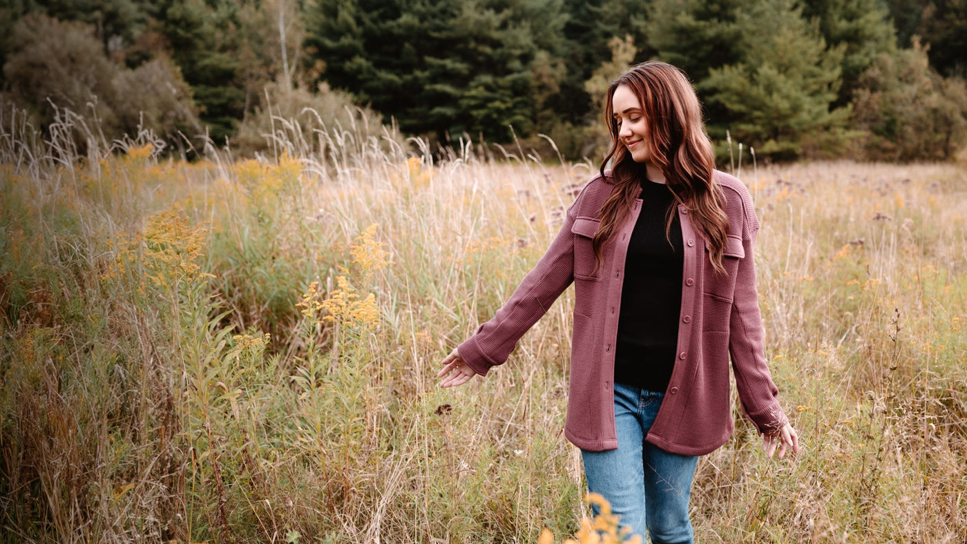 Model standing in field and wearing new Oaklynn shacket in wild ginger color