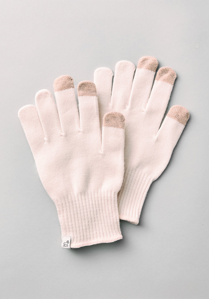 A pair of Woolx Asher Tech Gloves in an Almost Mauve shade, designed for touchscreen use with contrasting beige fingertips, is displayed flat on a light gray background. The gloves are equipped with ribbed cuffs and one glove features a small tag with the brand logo.