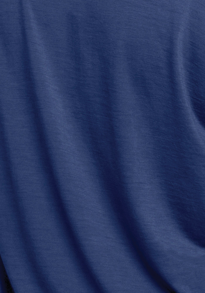 A close-up of the blue fabric with gentle folds highlights its smooth texture and soft appearance. This material, used in the Woolx Desi Nightgown - Starry Night, is evenly colored, lightweight, and breathable—perfect for keeping hot sleepers cool.