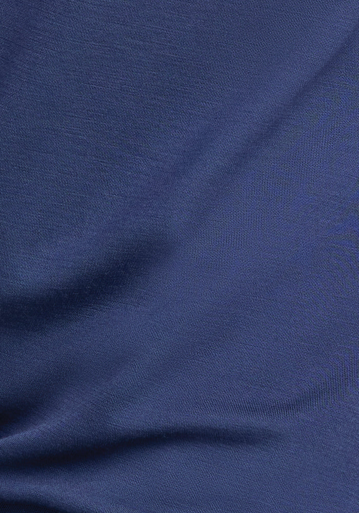 Close-up of a dark blue fabric with a smooth, anti-wrinkle texture. The material appears to have soft folds, creating slight variations in light and shadow across the surface, reminiscent of the Parker Sweatpants - Starry Night by Woolx, known for their temperature-regulating properties.