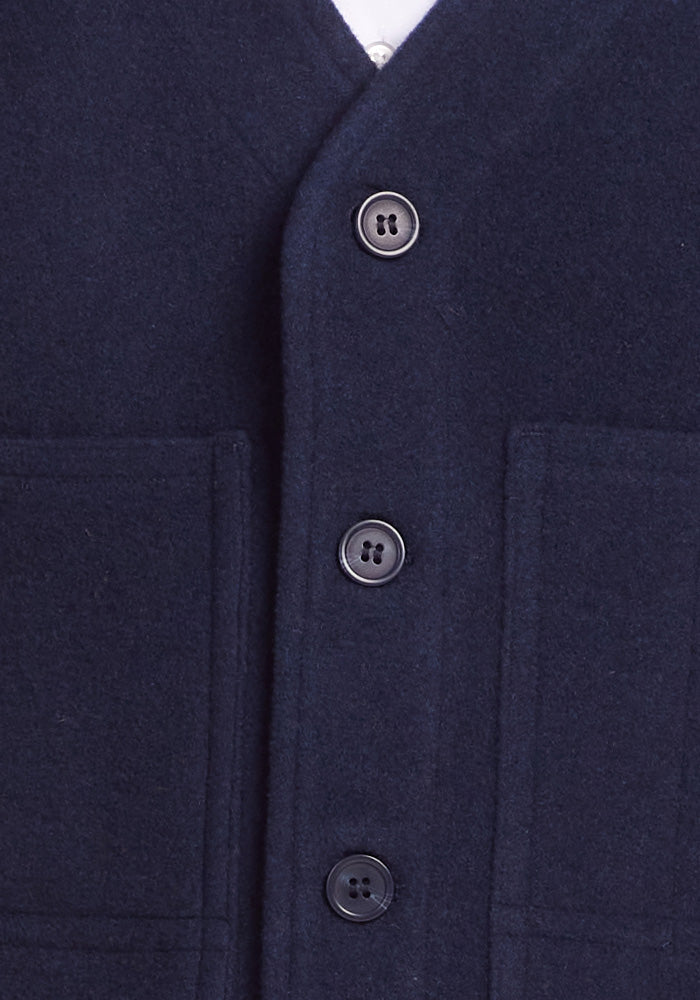 Close-up of the Baker Vest in dark navy by Woolx, featuring four dark buttons and two front pockets. The central button closure showcases the Boucle knit fabric texture, while its V-neck design adds an element of sophisticated insulation.