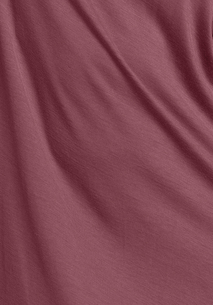 Close-up of the soft, wild ginger-colored fabric of the Desi Nightgown from Woolx, showcasing gentle folds that create smooth curves and shadows while providing cooling comfort and moisture-wicking properties.