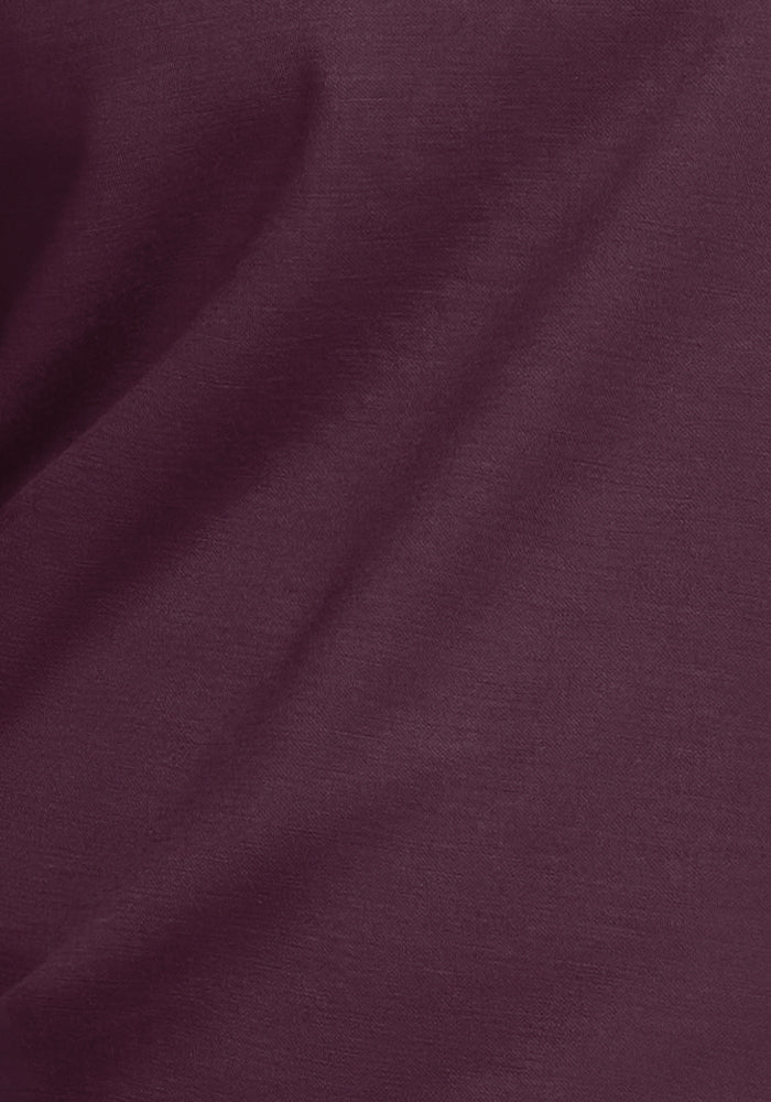 Close-up of a dark maroon fabric, revealing its smooth texture and gentle folds. This Woolmark® Certified material is ideal for the Parker Sweatpants - Wine Tasting by Woolx, providing a luxurious feel and temperature-regulating comfort as merino wool sweatpants.