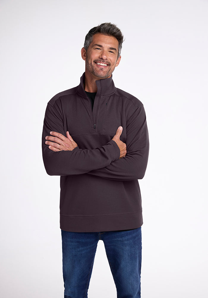 An older gentleman with short gray hair and a beard smiles confidently, arms crossed, wearing the Wool Aire™ Mason in Chocolate Plum by Woolx. He pairs it stylishly with blue jeans while standing against a plain white background.