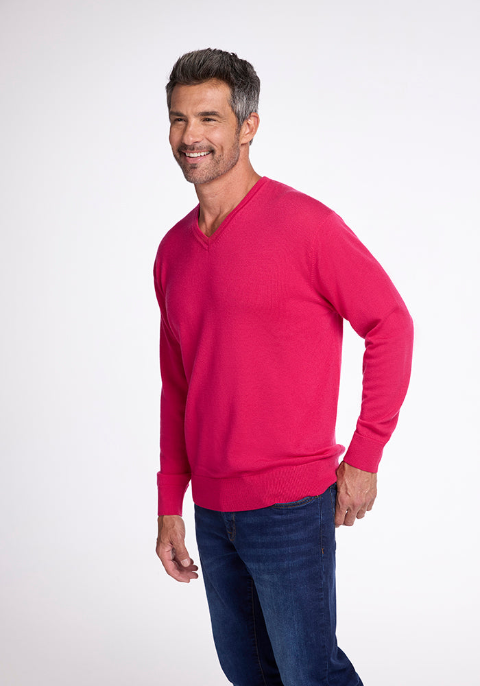 A smiling man with gray hair is wearing the Vincenzo Sweater in Berry Burst by Woolx and blue jeans. He is standing against a plain white background.