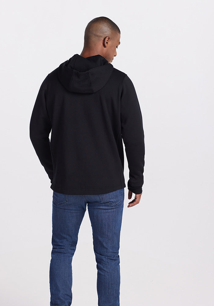 A person wearing the Woolx Grizzly Sweatshirt in black and blue jeans is facing away from the camera, showing the back view. The background is plain white, and their head is slightly turned to the left.