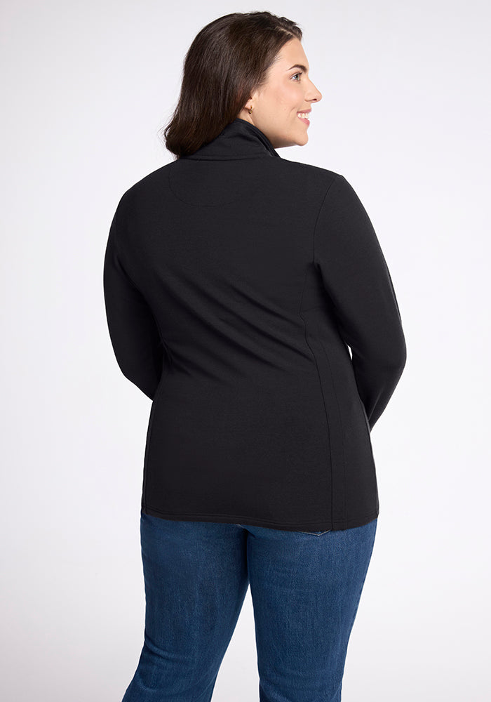 A person with long dark hair is seen from behind, standing against a plain white background. They are wearing the flattering Finley Zip Up Sweatshirt - Black by Woolx, made of Australian merino wool, paired with blue jeans and their hands at their sides.