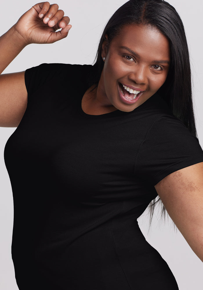 A cheerful person with long hair strikes a playful pose, wearing the energy-boosting Addie Short Sleeve Crew by Woolx, an odor-free Merino tee.