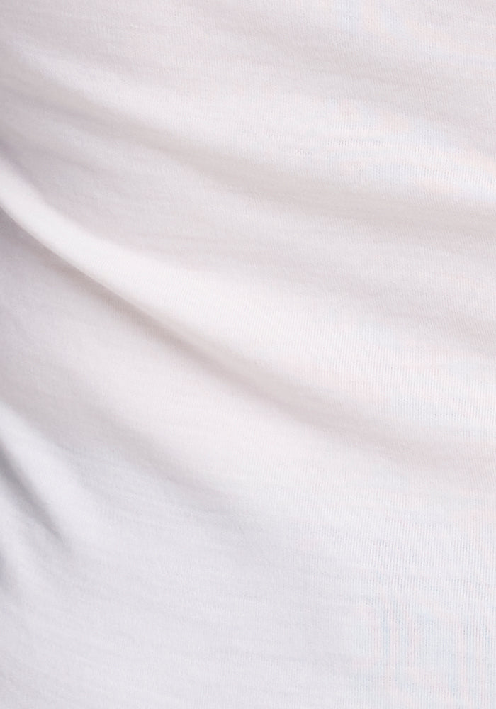 Close-up image of the Eva Tunic - Buttercream by Woolx, showcasing the Merino wool fabric with visible folds and texture. The material looks smooth and soft, creating natural shadows and slight ripples that evoke a touch of street style elegance.