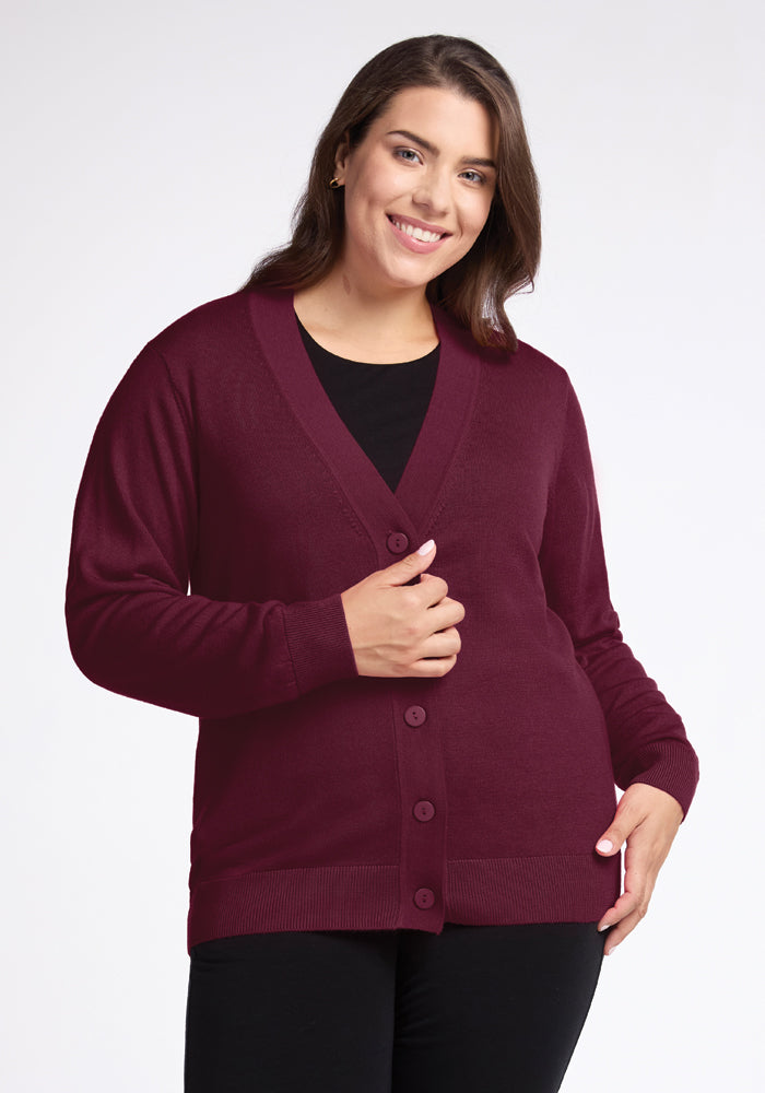 A person smiling and wearing the Gia Sweater in Cabernet Crush by Woolx over a black shirt, standing against a plain white background. 