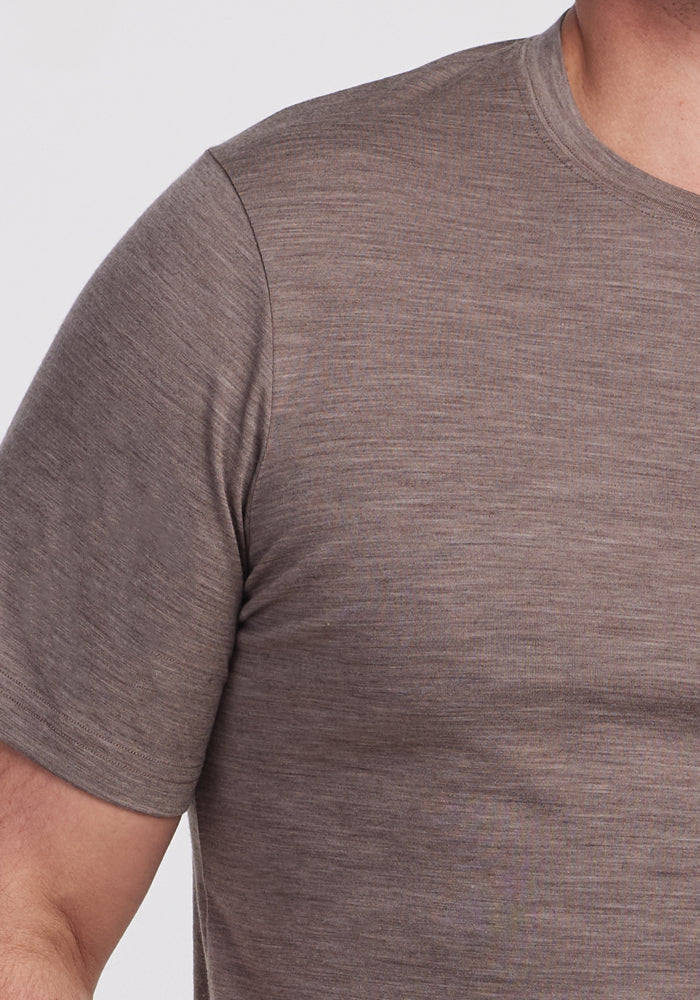 Close-up of a person wearing a Simply Taupe Endurance Tee by Woolx, featuring short sleeves and crafted from textured Merino Wool. The image highlights the fabric and cut, showcasing part of the shoulder and chest against a plain, light background. Ideal performance gear for everyday comfort.