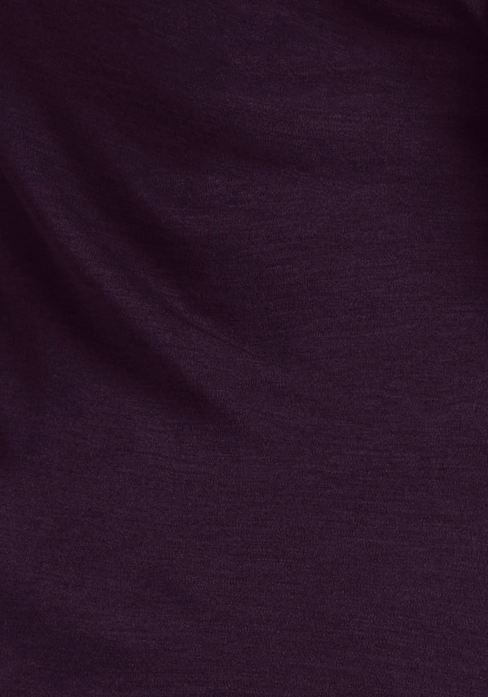 A close-up of the Layla V Neck Top in Deep Plum from Woolx, showcasing its dark purple Merino wool fabric with a smooth texture and subtle draping. The material looks soft and slightly stretchy, similar to a featherweight tee, forming gentle folds and shadows.