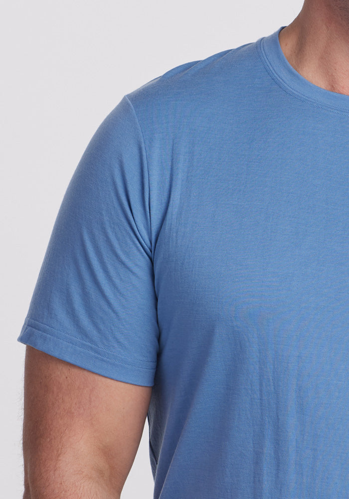 A person wearing the Woolx Endurance Tee in Coronet Blue, ideal for performance gear, stands against a plain background. Only their upper torso is visible.