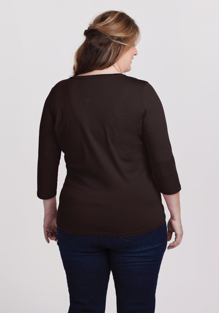 A woman with long, light brown hair stands facing away, wearing the Woolx Jenny 3/4 Sleeve Crew Neck in French Roast and dark blue jeans. The background is plain white.