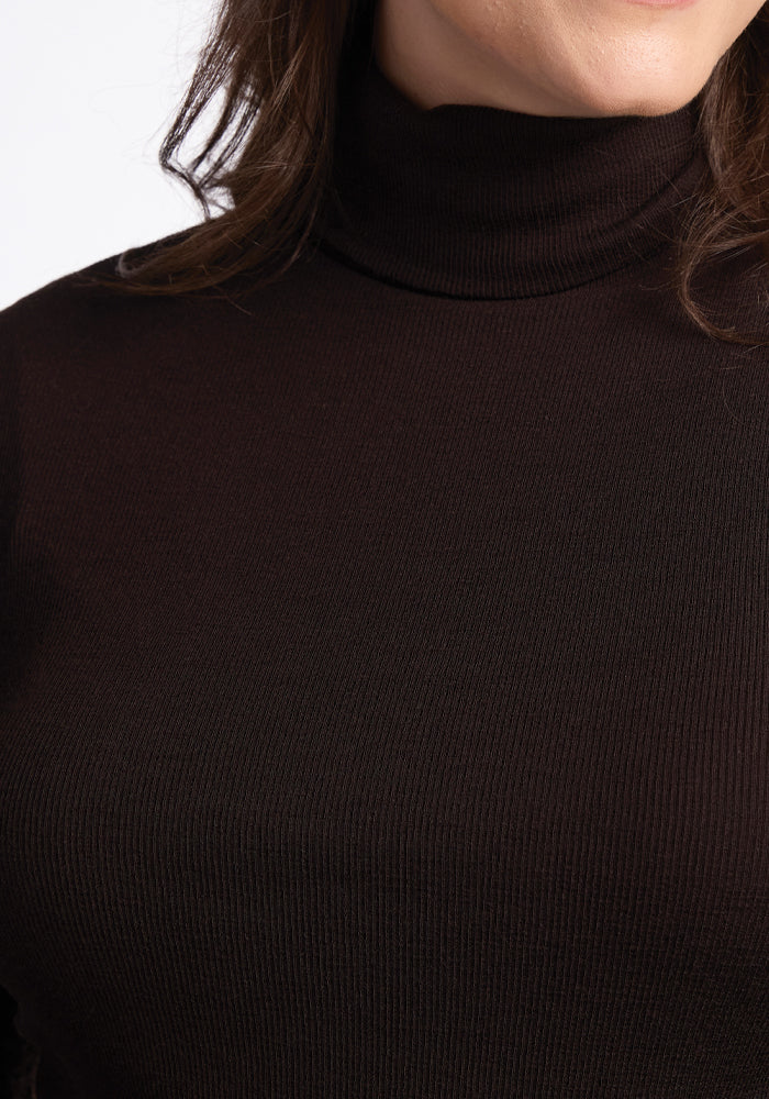 A person wearing a Woolx Sage Ribbed Turtleneck in the French Roast color is partially visible, with brown hair cascading over their shoulders. The photo focuses on the upper torso, emphasizing the texture of the ribbed fabric.