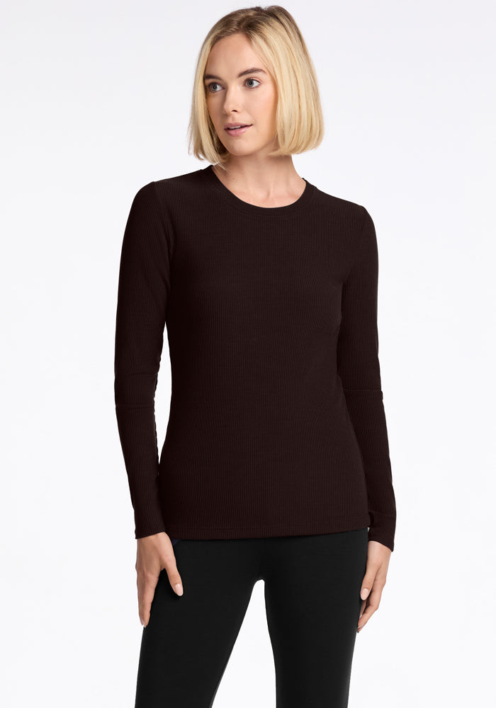 A person with short blonde hair is wearing a French Roast Hadley Ribbed Crew from Woolx, along with matching pants. The luxurious ribbed design adds an elegant texture as they stand against a white background, looking to the side. 