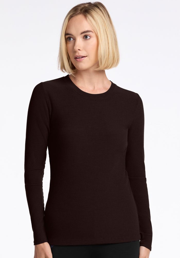 A person with blonde hair is wearing a simple black top similar to the Hadley Ribbed Crew in French Roast by Woolx, crafted from luxurious Merino wool. They are standing against a plain white background with a neutral expression on their face.