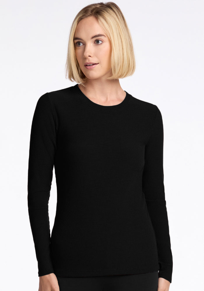 A person with short blonde hair wears the Woolx Hadley Ribbed Crew in black, gazing slightly to the side. The background is plain white.