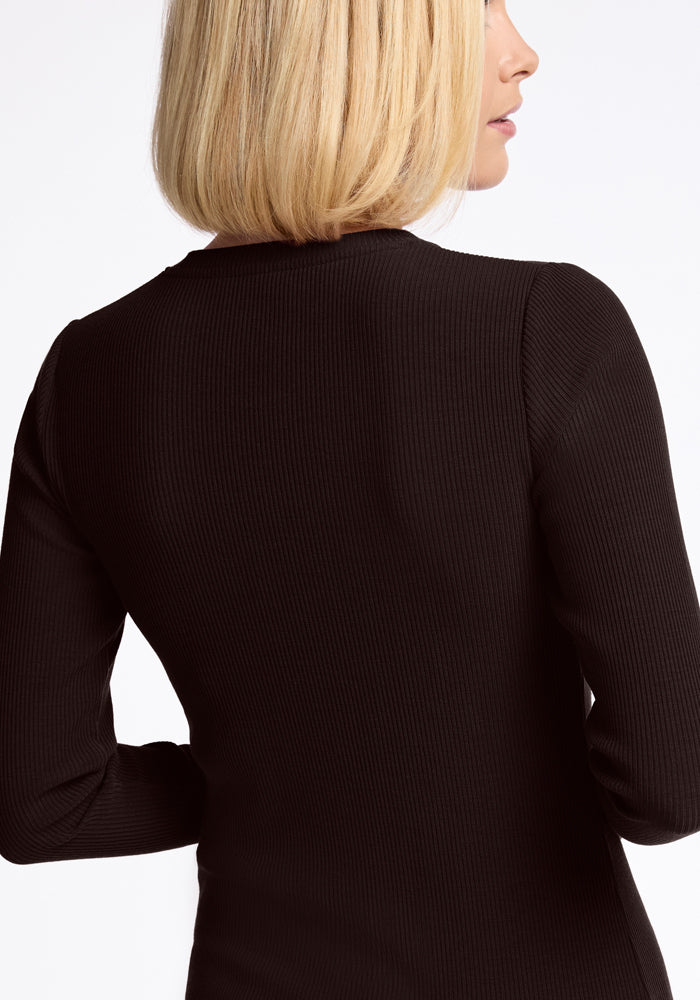 A person with blonde hair is facing away from the camera, wearing a Hadley Ribbed Crew in French Roast. The image highlights the luxurious ribbed design and showcases the back and part of the side of this elegant piece by Woolx.