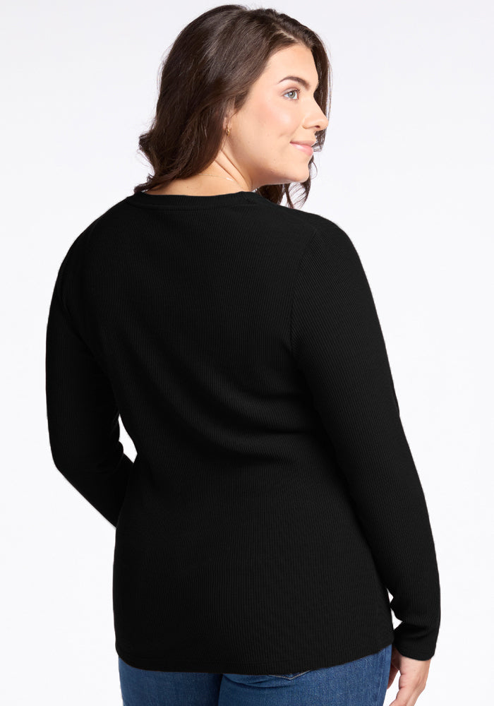 A person with long brown hair is wearing the luxurious-feel Hadley Ribbed Crew in black by Woolx and blue jeans, standing and facing away from the camera against a plain white background.