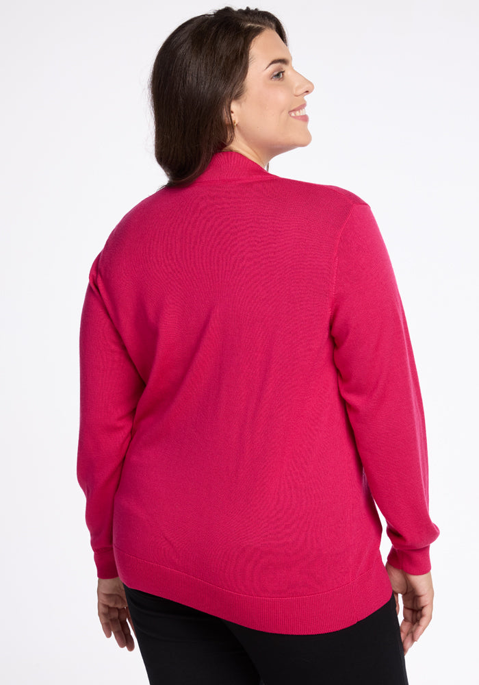 A person with long dark hair, turned slightly to the side and smiling while looking off-camera, is wearing the vibrant Berry Burst Gia Sweater by Woolx against a plain white background.