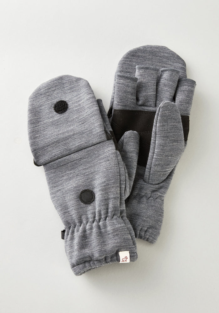 Introducing the Cameron Glove Mitten - Graphite Heather by Woolx: these gray mittens feature black circular patches on a light gray background. Crafted from a soft merino wool blend, they include an adjustable strap for added comfort and style.