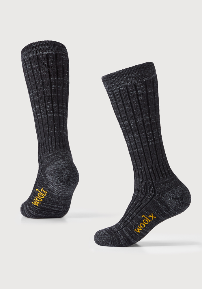 A pair of dark navy marled Joey Socks with a ribbed texture stands upright. Featuring the brand name "Woolx" in yellow lettering on the toes and heels, these Woolmark Certified socks are made from luxurious Australian Merino Wool. They are displayed against a plain white background.