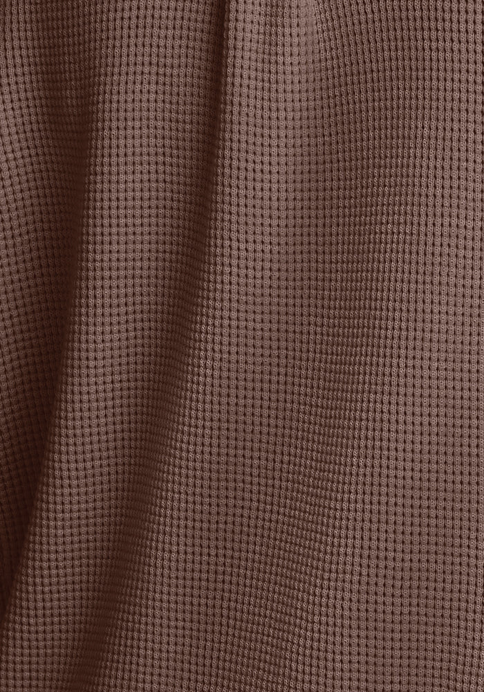 Close-up of the Oaklynn Waffle Shacket in Latte by Woolx, featuring textured Merino wool fabric with a delicate checkered pattern. The material drapes effortlessly, forming soft folds and shadows across the surface, ideal for layering.