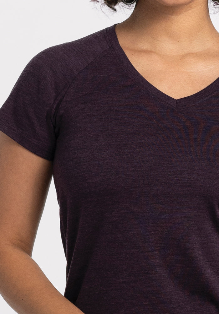 A person wearing a deep plum Mia V Neck by Woolx. The image captures the upper body and shoulders against a light gray background, showcasing the perfect Travel Athletic Tee.