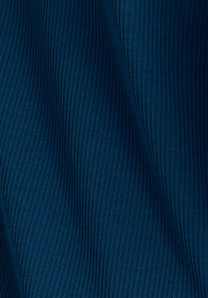 Close-up of a textured fabric in Real Teal with vertically aligned ridges. The Merino wool weave by Woolx creates a wavy, flowing pattern that adds depth and dimension to the design, making the Evie Tunic perfect for a cozy and flattering fit.