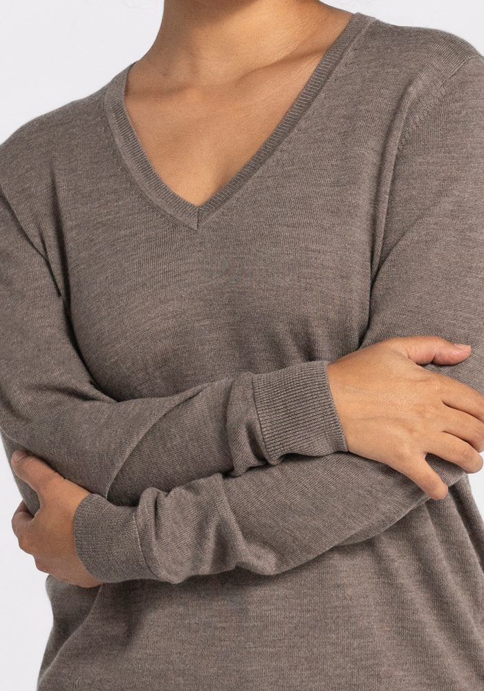 A person wearing the Francesca Sweater in Sable by Woolx stands with their arms crossed. The focus is on the upper body, highlighting the texture of the sweater against a neutral background.