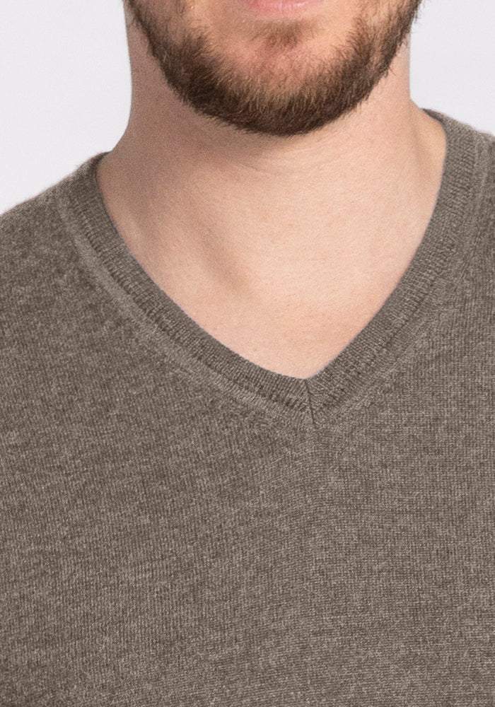 The image showcases a person in a Vincenzo Sweater - Sable by Woolx, highlighting the clothing with only the lower part of their face and neck partially visible.