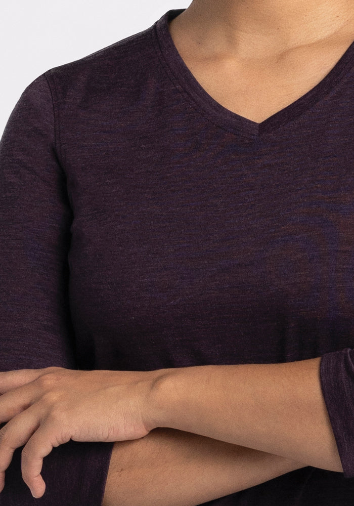 A person wearing the Woolx Elena V Neck in Deep Plum, featuring a relaxed fit, stands with arms crossed in front of their torso against a plain background.