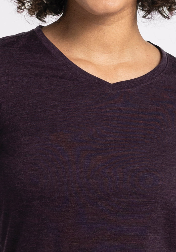 A close-up of a person wearing the Woolx Elena V Neck in Deep Plum. Made from Merino Wool, its texture and relaxed fit are beautifully highlighted against a neutral gray background.