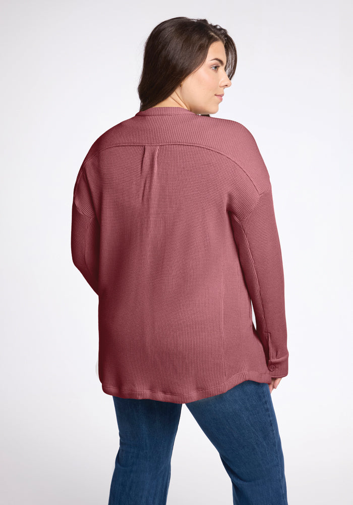 A person with long brown hair is turned slightly to the side, wearing the Oaklynn Waffle Shacket in Wild Ginger by Woolx and blue jeans. The individual stands against a plain white background, exuding an earthy charm.