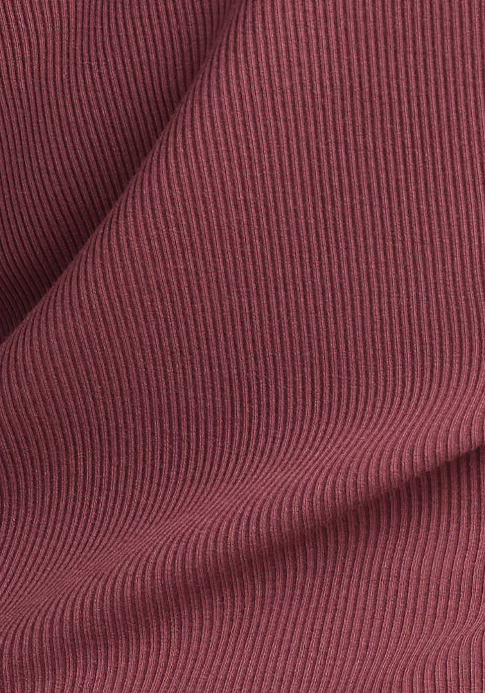 Close-up of a wild ginger fabric with thin, vertical ribbed texture, characteristic of the Merino wool used in the Woolx Hadley Ribbed Crew. The material is gently folded, creating soft waves and shadows that enhance the texture and depth of the fabric.