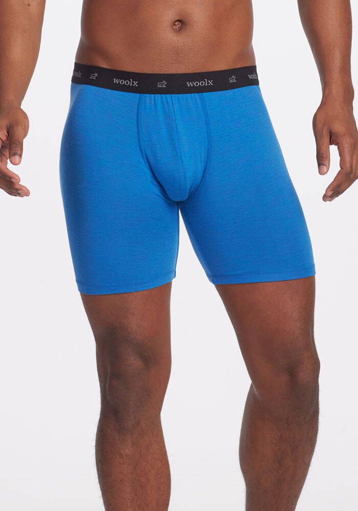 A person wearing indigo Jazzy No Fly Boxer Briefs OLD by Woolx, featuring a black waistband with "woolx" inscribed on it. These merino wool boxers offer a no-fly design against a plain white background.