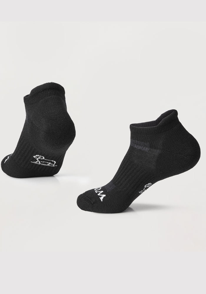 The Rowan No Show Tab Lightweight Socks in black from Woolx are displayed on a light gray background. Crafted with Merino wool, these socks feature subtle white logos near the toes and heels, offering remarkable temperature regulation and cushioned ultimate comfort.