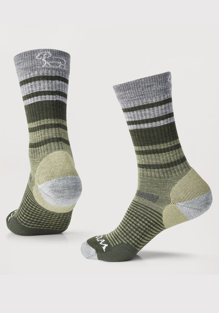 Two odor-resistant Everyday Light Cushion Crew Socks from Woolx in the Moss Stripe color are displayed. These durable socks, with reinforced heels and toes, feature various shades of green and gray stripes crafted from merino wool. One sock is shown from the front and the other from the back, highlighting their horizontal striped design and textured foot pattern.