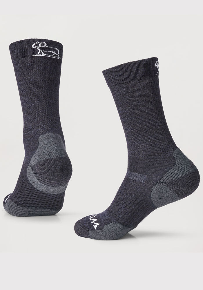 Displayed are two pairs of Harbor Crew Socks Light Cushion by Woolx in navy blue, featuring reinforced gray heels and toes. They boast a subtle pattern and branding near the top. One sock stands upright, while the other is shown from behind to highlight the details of these durable outdoor essentials.