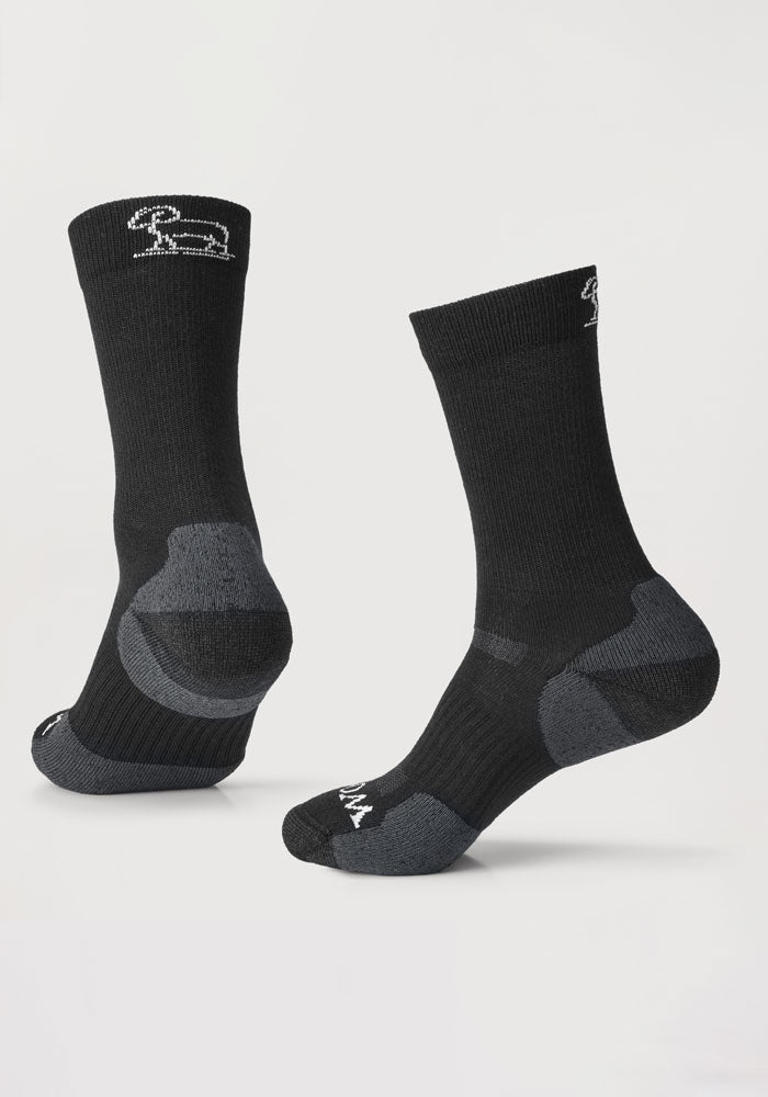 The Harbor Crew Sock Light Cushion - Black by Woolx features moisture-wicking technology, with gray heel and toe accents. A small embroidered rabbit logo is visible near the cuff of these Merino wool socks, showcased on a neutral background, providing both style and comfort.