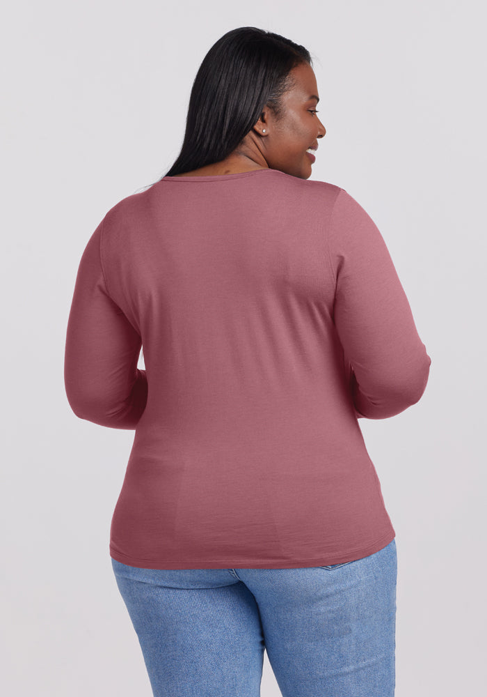 A person wearing the Remi Long Sleeve T-Shirt in Wild Ginger by Woolx along with light blue jeans stands with their back facing the camera against a plain background.