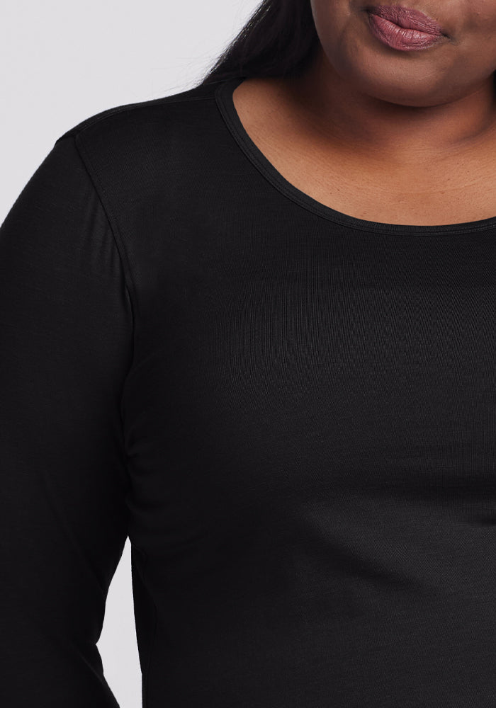 A person wears the Woolx Remi Long Sleeve T-Shirt in black, highlighting its soft Merino wool texture and neckline. The shirt is odor-resistant and the focus is on the upper body against a plain, unobtrusive background.